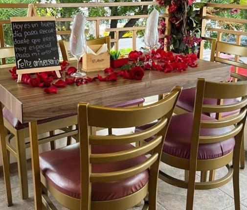 Mesa con pétalos de rosa y pizarra de feliz aniversario
