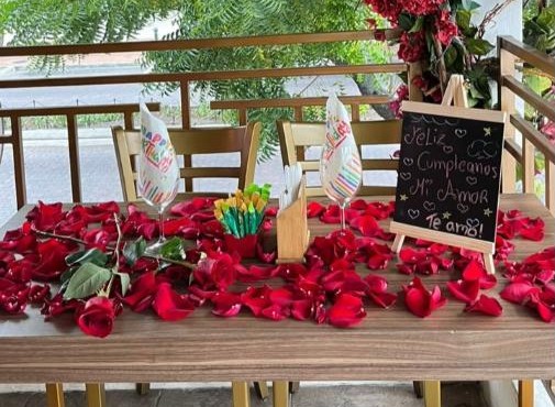 Mesa con rosas y pizarra de feliz cumpleaños mi amor